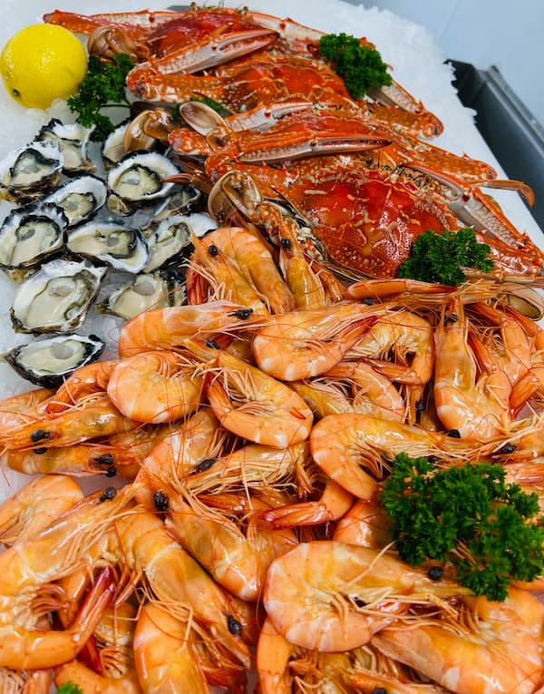 Fresh seafood selection at Wallis Lake Fishermen's Co-op, featuring vibrant cooked crabs, prawns, and oysters, beautifully arranged with parsley and lemon garnish.