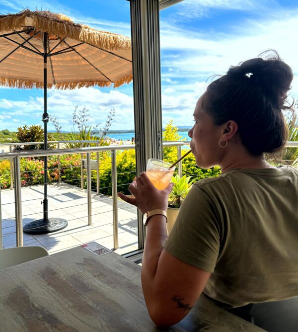 Guest enjoying a refreshing cocktail at Si Señorita in Forster, with stunning views of Wallis Lake, a vibrant dog-friendly outdoor area, and lush surroundings.